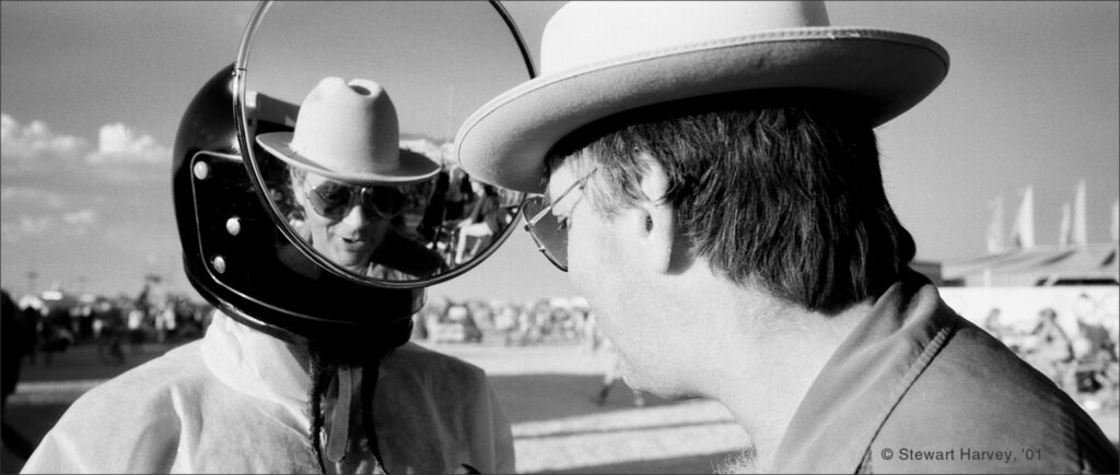 Larry Harvey looking at his reflection in a round mirror in 2001.