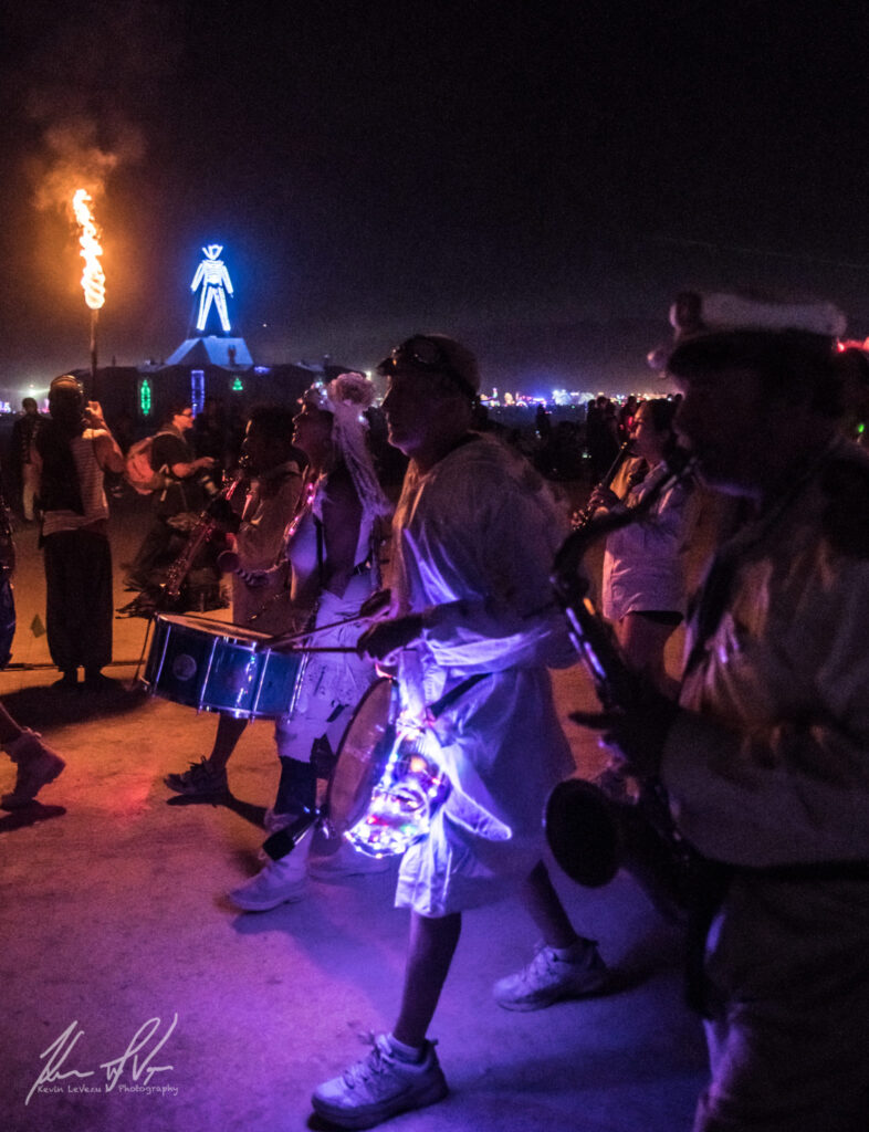 Musicians playing the drums and walking near the fire conclave.