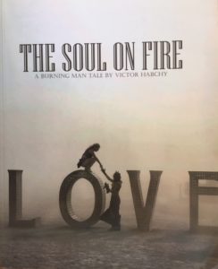 LOVE art piece at Burning Man, with a person on top of the O and a person standing next to it