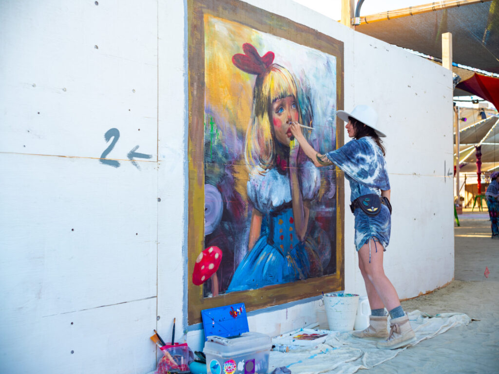 Woman painting a mural on the back of Center Camp