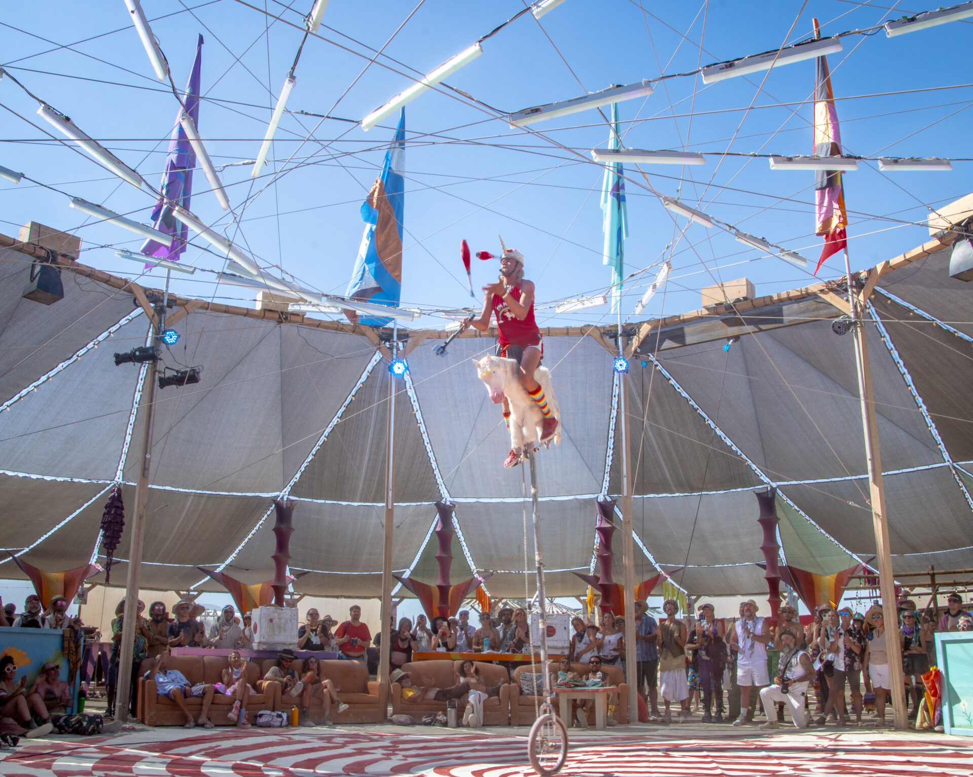 Person riding a 12-foot unicycle in the Center Camp Canopy.
