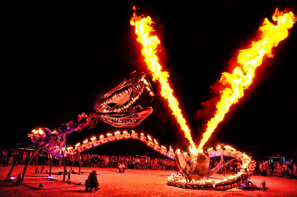 A metal serpent wraps around an egg that is shooting two steams of flaming methanol into the air.