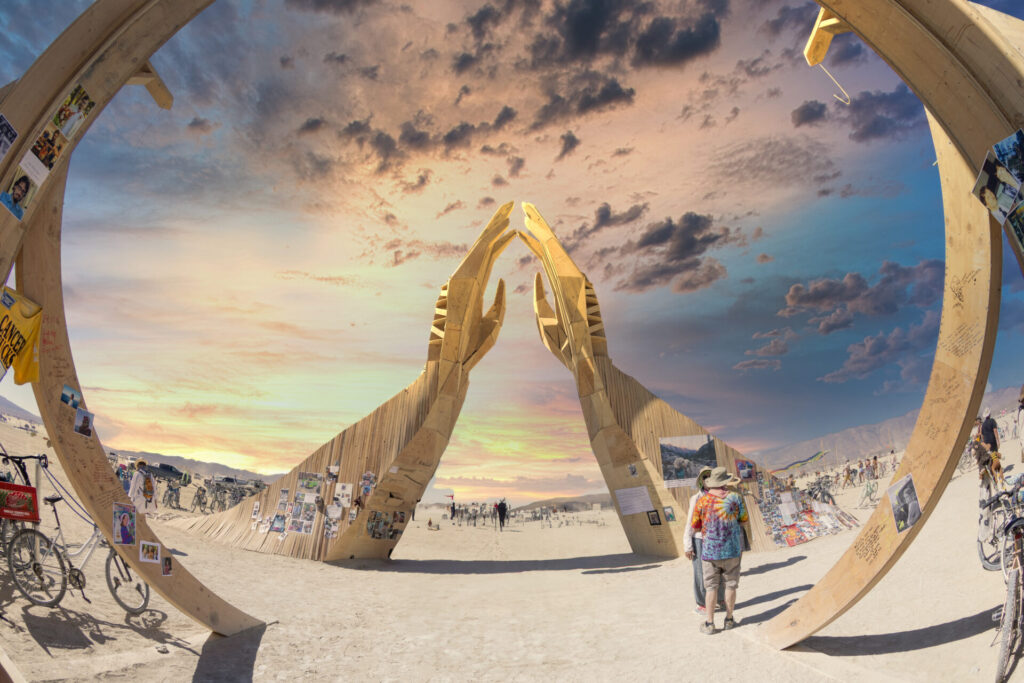 Two arms extend out of the ground, fingers touching, creating a triangular opening.