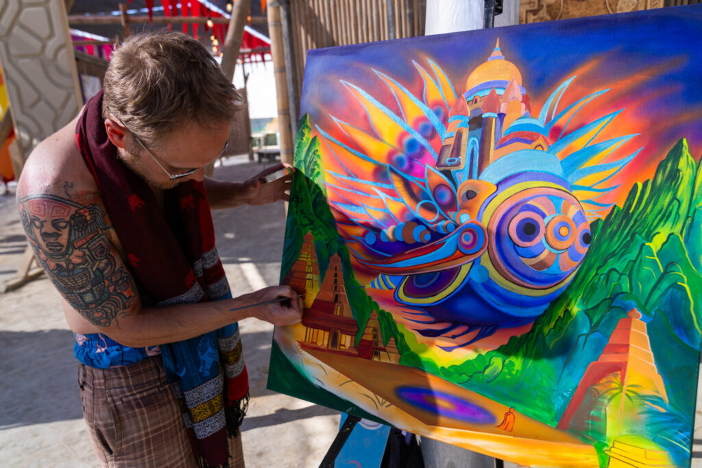 A participant paints a colorful abstract landscape on canvas