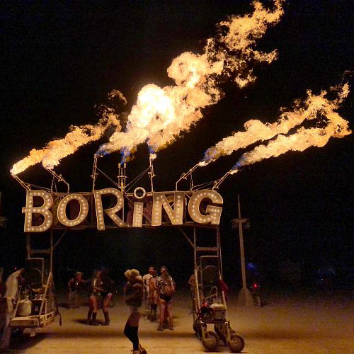 Seven streams of fire above large metal letters that spell "Boring"