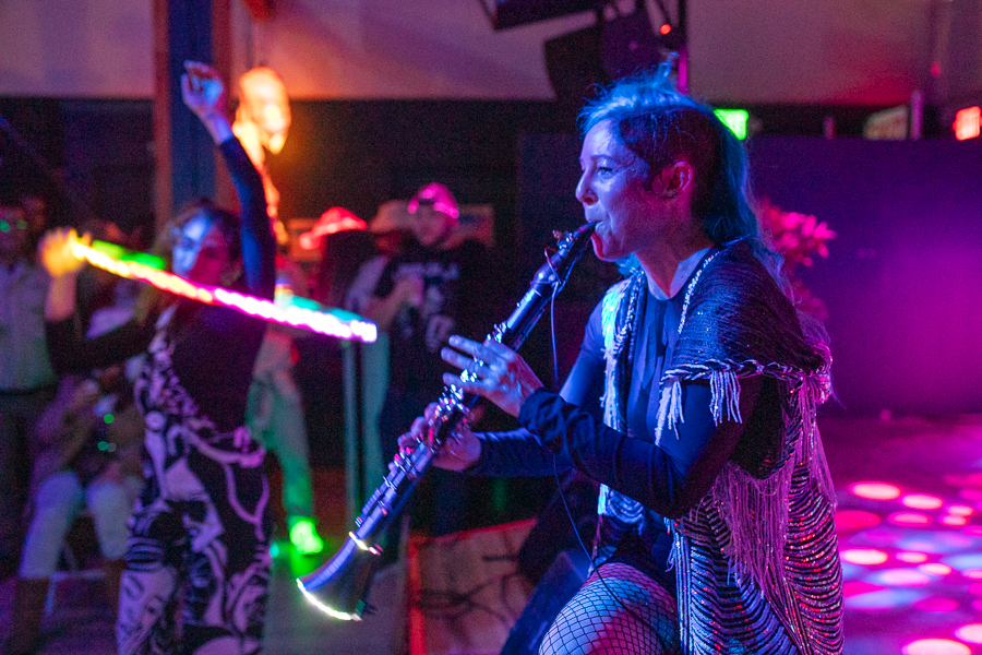 A clarinet player foreground and a lighted hula hoop dancer in the background