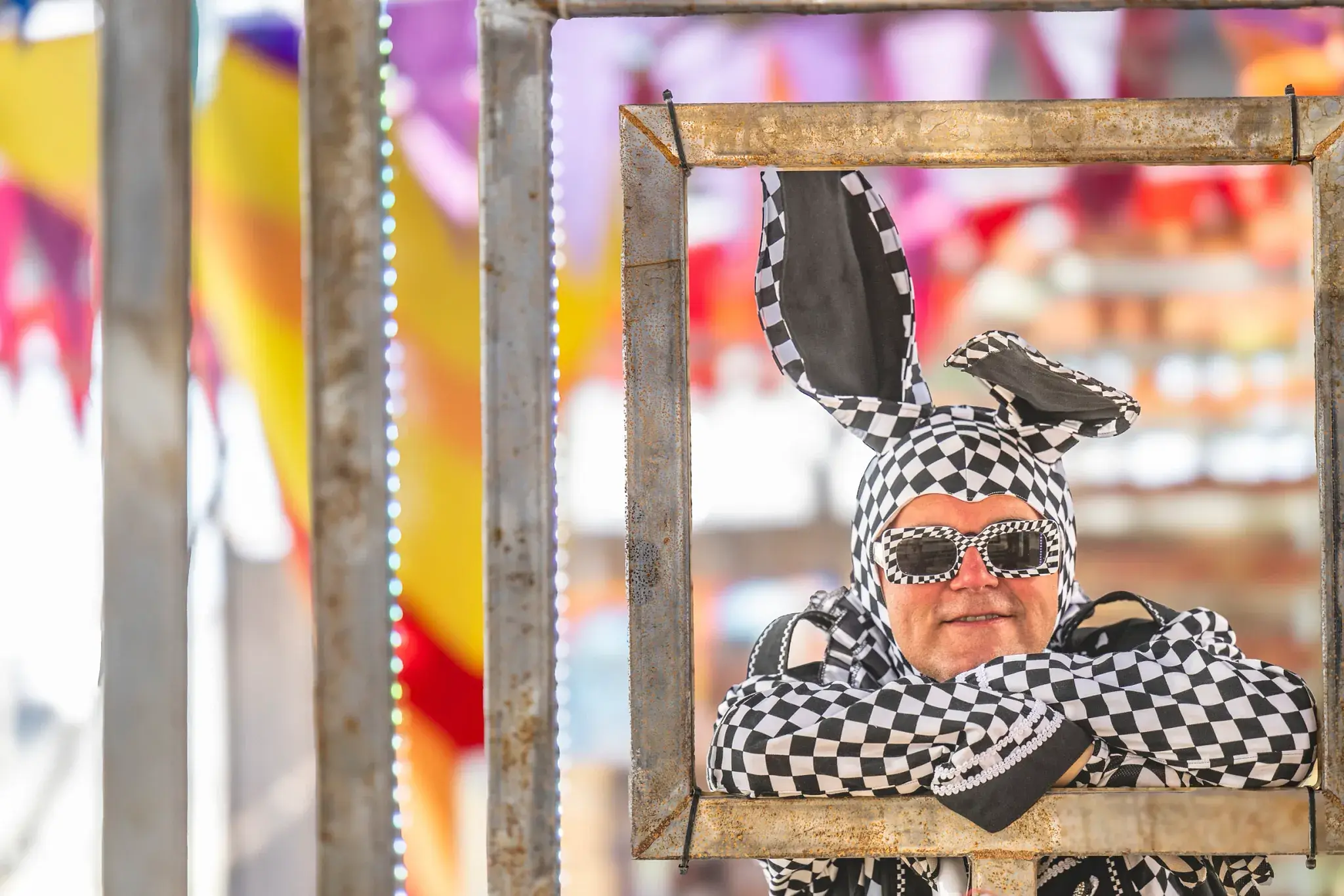 A person in a checkered bunny costume smiles at the camera