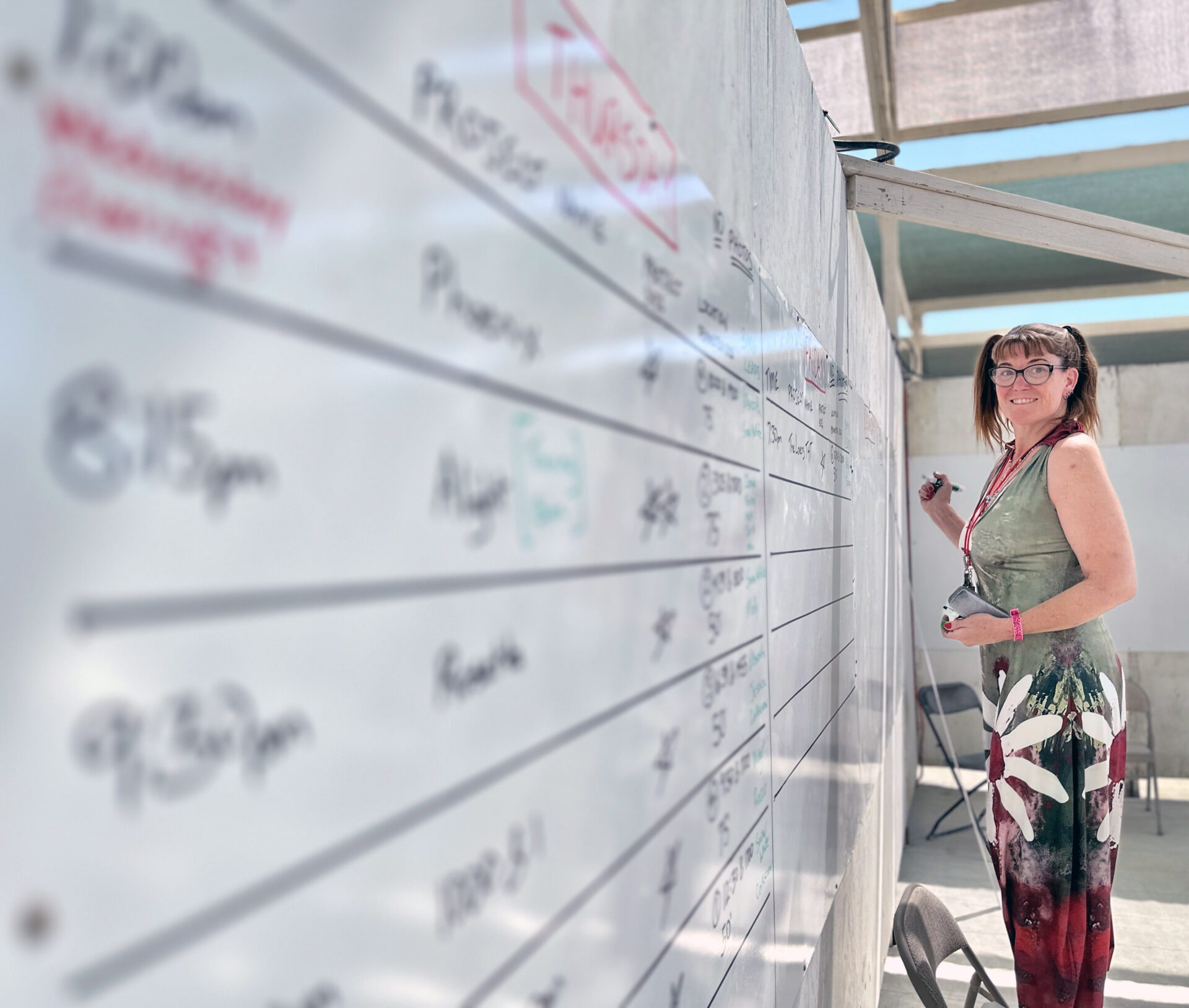 Volunteer holding a marker stands by a long whiteboard