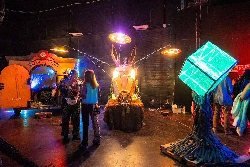 two humans in warehouse standing next to lit up horse mutant vehicle with light up art tree
