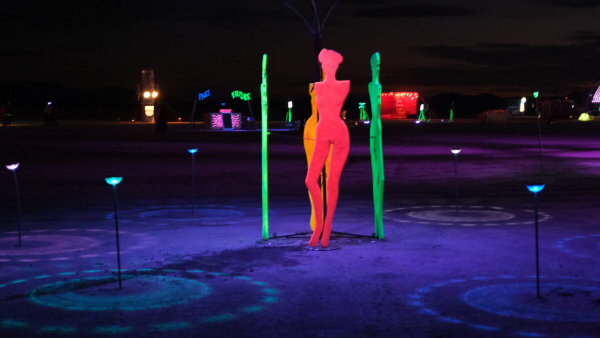 Silhouettes of four people, painted in neon colors under blacklight