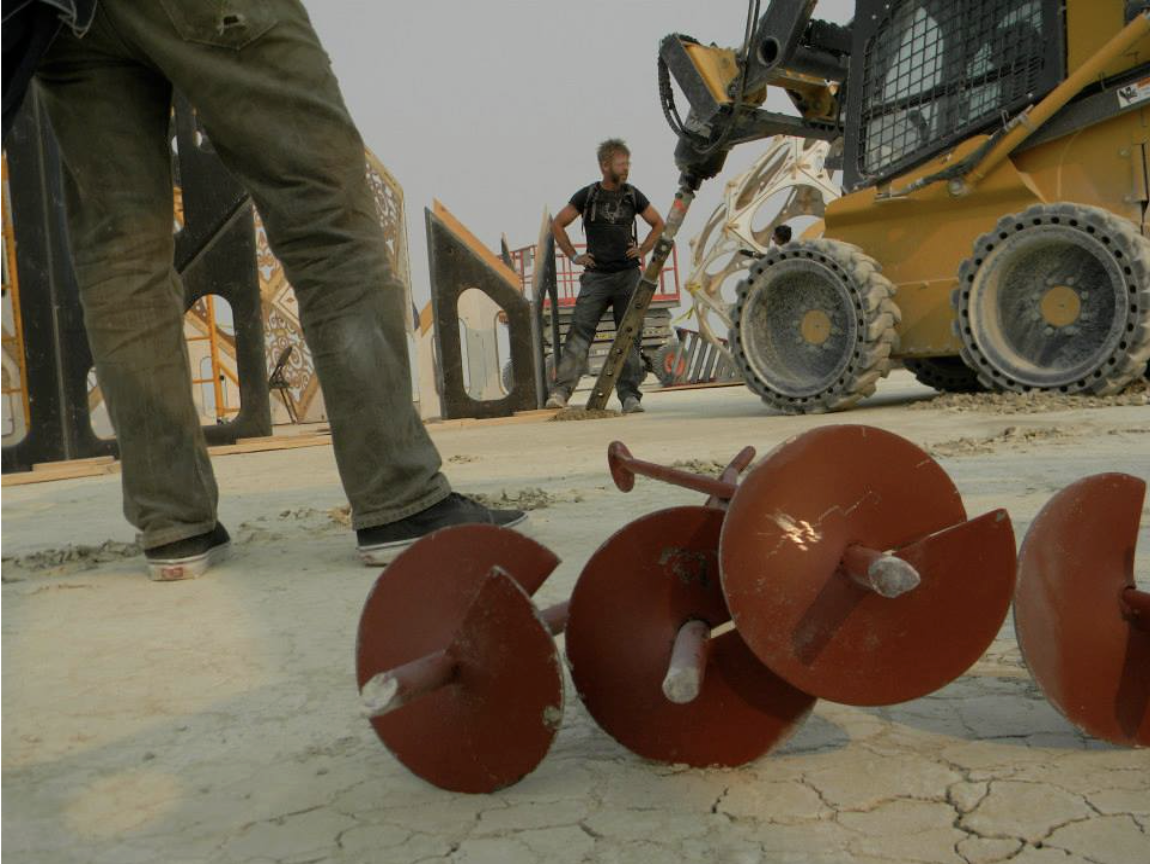 Heavy equipment in the background helical ground anchors in the foreground.