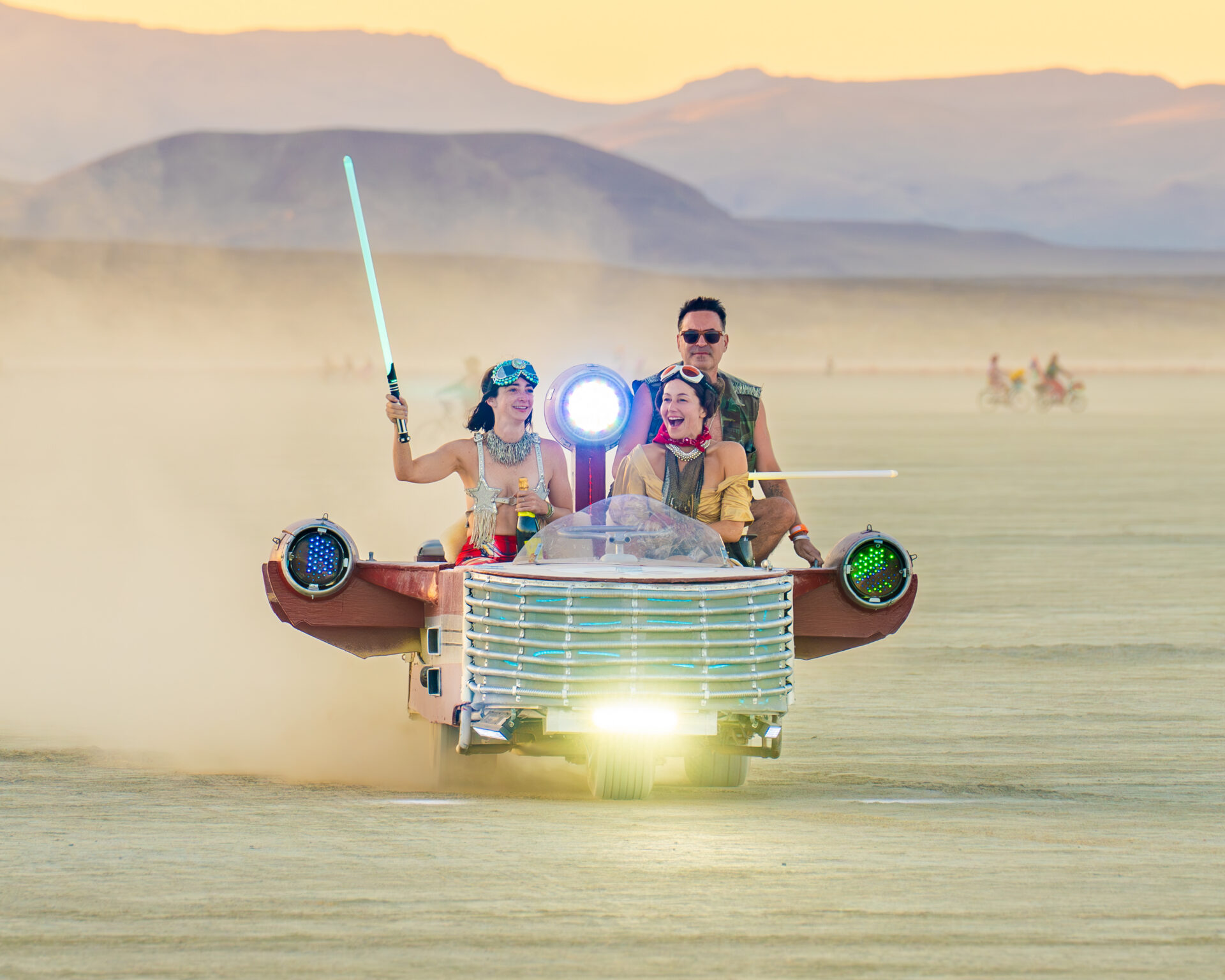 A star wars inspired mutant vehicle races across open playa at sunrise.